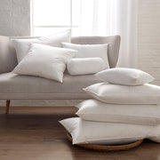 Montreux three-chamber down pillows stacked on a sofa and floor.