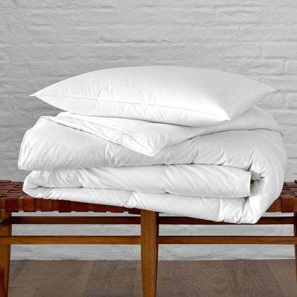 White Valletto down comforter folded on a woven bench.