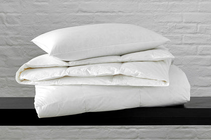 Montreux down pillow and folded comforter stacked on a shelf.