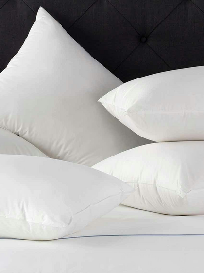 White down pillows stacked against a dark tufted headboard.