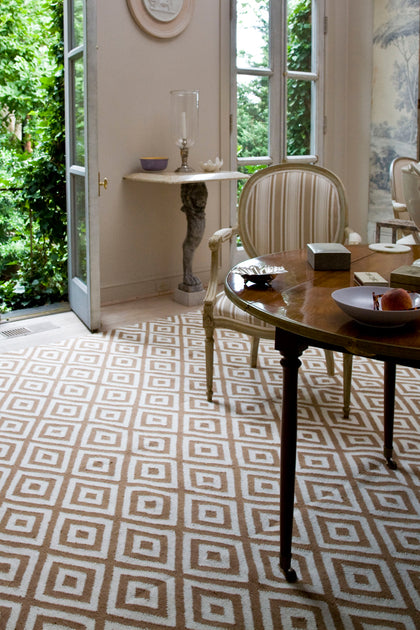 Living room styled with a diamond-patterned area rug in front of French doors.