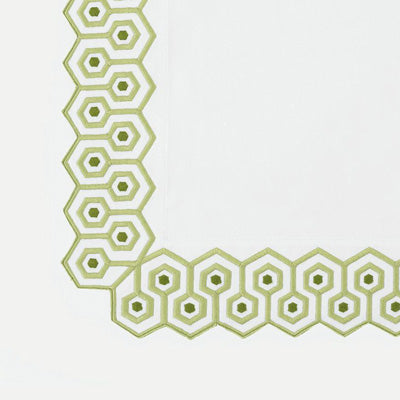 Close up of a napkin featuring a repeating green geometric border pattern along the left and bottom edges, forming an L-shaped corner design.
