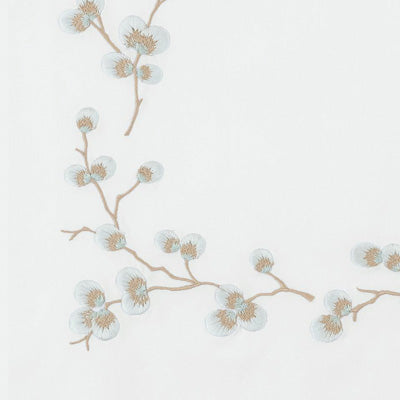 Close up of a napkin featuring a delicate, minimalist botanical pattern of light blue blossoms and tan branches.