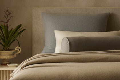 Venus cashmere bolster and oversized euro shams styled on a bed.