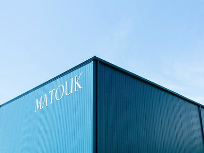 Exterior of the Matouk linens factory building with blue paneling and signage.