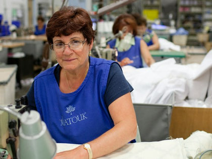 Matouk seamstress sewing fine linens on the factory production floor.