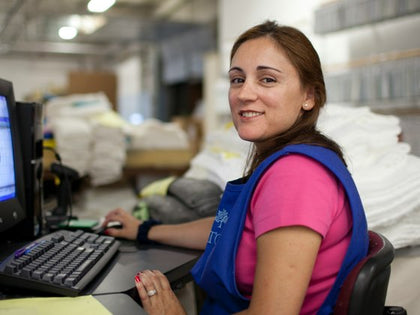 Matouk employee working at a desk surrounded by folded linens in the warehouse.