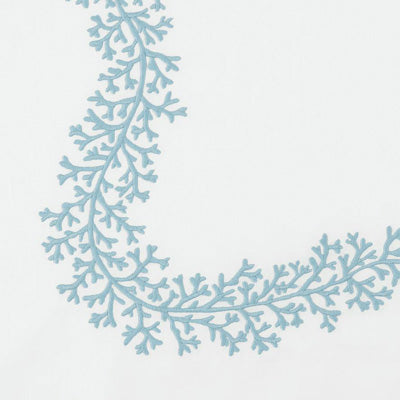 Close up of a napkin featuring a light blue coral or branching botanical pattern along the left side.