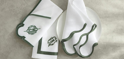 Ornate crest-style monogram on scalloped-edge table linens.