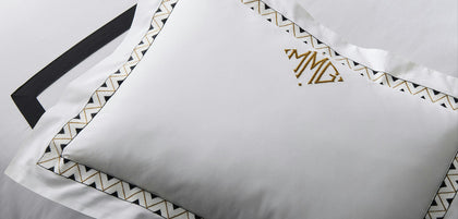 Triangular monogram with a chevron border trim on a pillow sham.