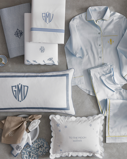 Flat lay of monogrammed pajamas, pillowcases, shams, and accessories