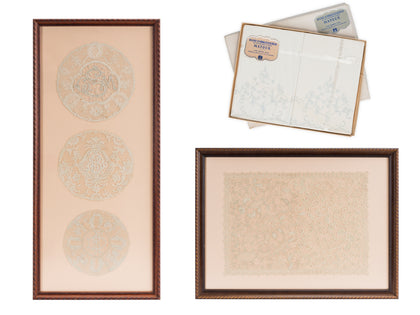 Framed antique hand-embroidered lace pieces displayed beside a vintage lace sample box.