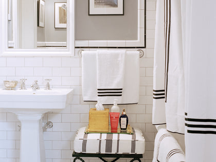 White subway-tile bathroom styled with Newport bath towels featuring a black striped border.