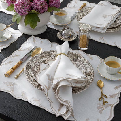 Marcella-print scalloped-edge placemats and napkins styled on a table with china and gold flatware