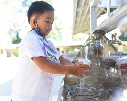 Child washing hands at an outdoor water station