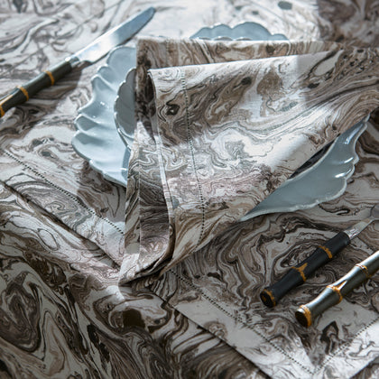 Balthazar marbleized napkin and placemat beside a scalloped plate