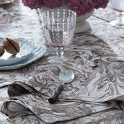 Balthazar marbleized napkin and spoon beside a pink stemmed glass