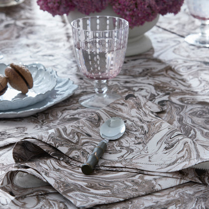 Balthazar marbleized napkin and spoon beside a pink stemmed glass