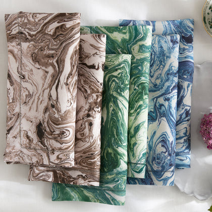 Folded Balthazar marbled napkins in brown, green and blue on a table.
