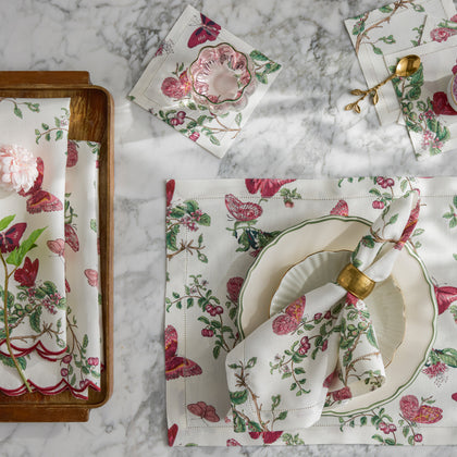 Baudin Butterfly print placemats and napkins with pink florals and butterflies, set with green-rimmed china.