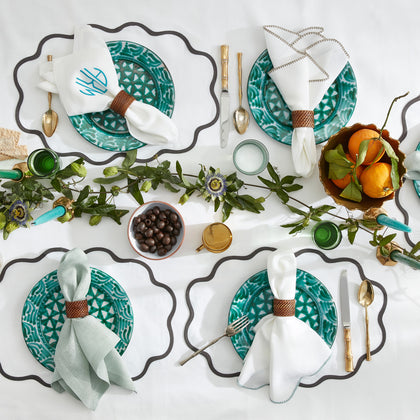 Chamant scalloped placemats set with green patterned plates, napkins, and citrus fruit.