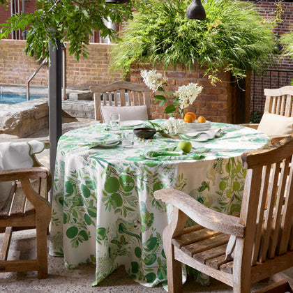 Green Citrus Garden print round tablecloth set on an outdoor patio table beside a pool.