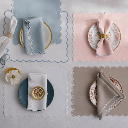 Dakota scalloped placemats in blue, pink, white, and tan, each set with a plate and napkin.