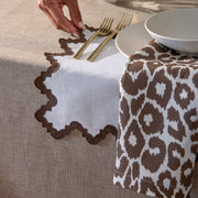 Brown Iconic Leopard napkin with a scalloped linen placemat and gold flatware