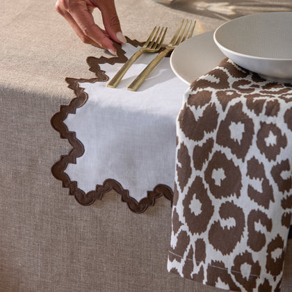 Brown Iconic Leopard napkin with a scalloped linen placemat and gold flatware