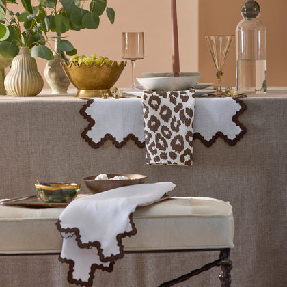 Brown Iconic Leopard napkin draped over scalloped placemats at a table