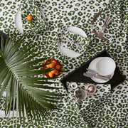 Green Iconic Leopard tablecloth set with plates, flatware, and palm fronds