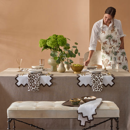Woman setting a table with brown Iconic Leopard napkins and placemats