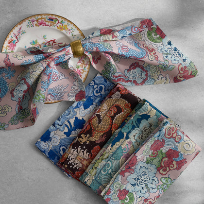 Magic Mountain dragon-print napkins folded on a table beside a floral dinner plate.