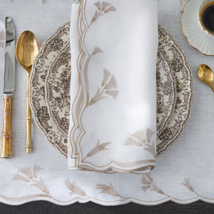 Scalloped Marcella napkin with gold floral embroidery on a place setting