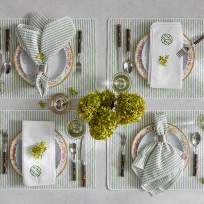 Green Matteo striped placemats and napkins set with floral china and green hydrangeas.