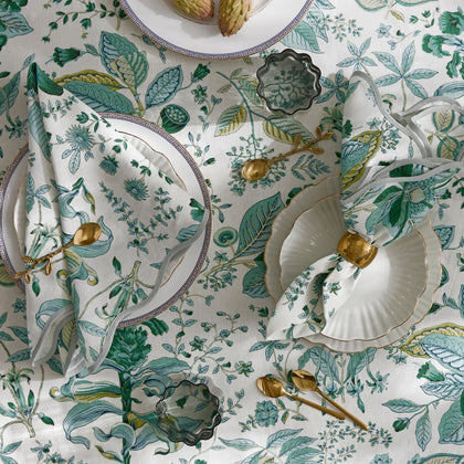Green Pomegranate botanical print tablecloth and napkins set with gold flatware and white china.