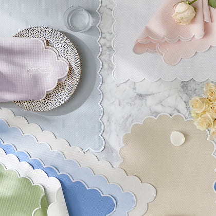 Savannah Gardens scalloped placemats in pastel colors, arranged flat with white roses.