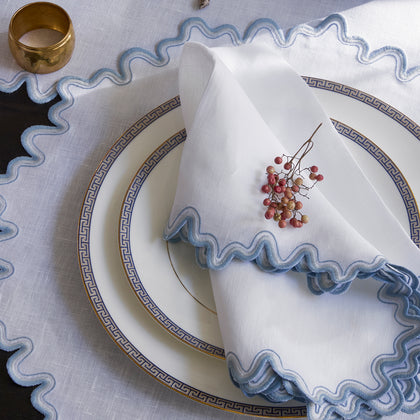White Wave scalloped placemat and napkin with blue wavy trim, set with greek-key bordered china.