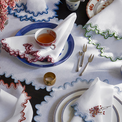 White Wave scalloped napkins with wavy trim in blue, red, and green, set with blue and white china.