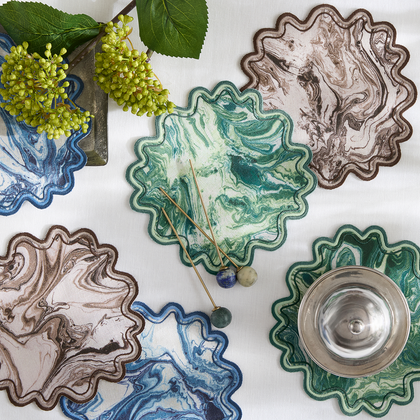 Scalloped Balthazar cocktail napkins with a marbled print on a table.