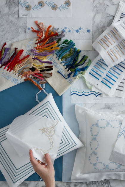 Custom embroidery swatches, colorful thread spools, and monogram pattern cards for bespoke linens