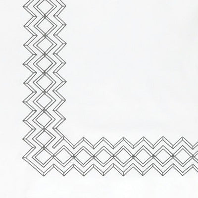 Close up of a napkin, featuring a black geometric zigzag border pattern along the left and bottom edges.
