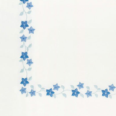 Close up of a napkin with a decorative border of small blue flowers and pale blue leaves running along the left and bottom edges.