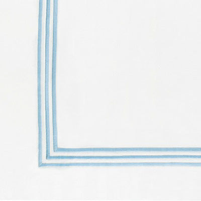 Close up of a napkin featuring a delicate double border in light blue along the left and bottom edges.