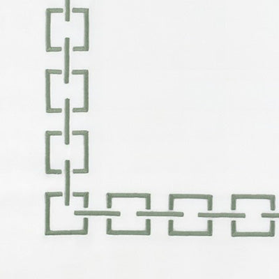 Close up of a napkin with a muted sage green geometric chain-link border pattern along the top and left edges.