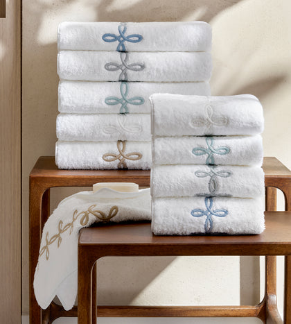 White Gordian Knot towels with an embroidered trim, stacked.