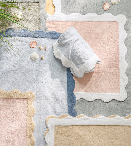 Scalloped bath mats in pastel colors with seashells.