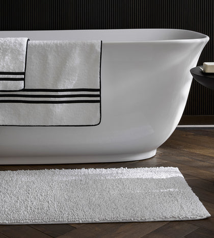 White Newport towel with a black stripe border, on a bathtub.