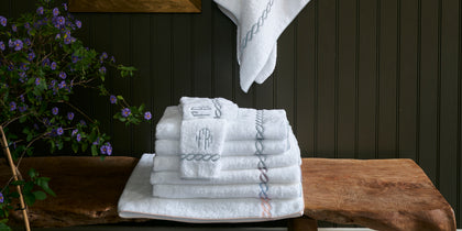 White Classic Chain towels with an embroidered trim and monogram, stacked.