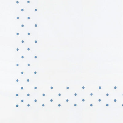 Close up of a napkin featuring a blue polka dot border along the left and bottom edges.